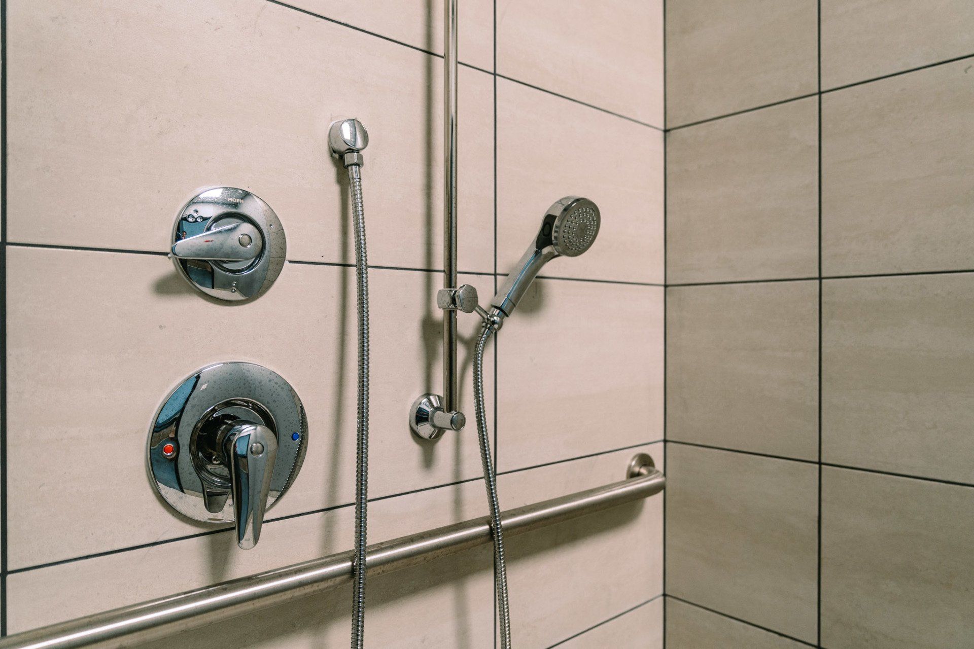 A shower with a hand rail and a shower head