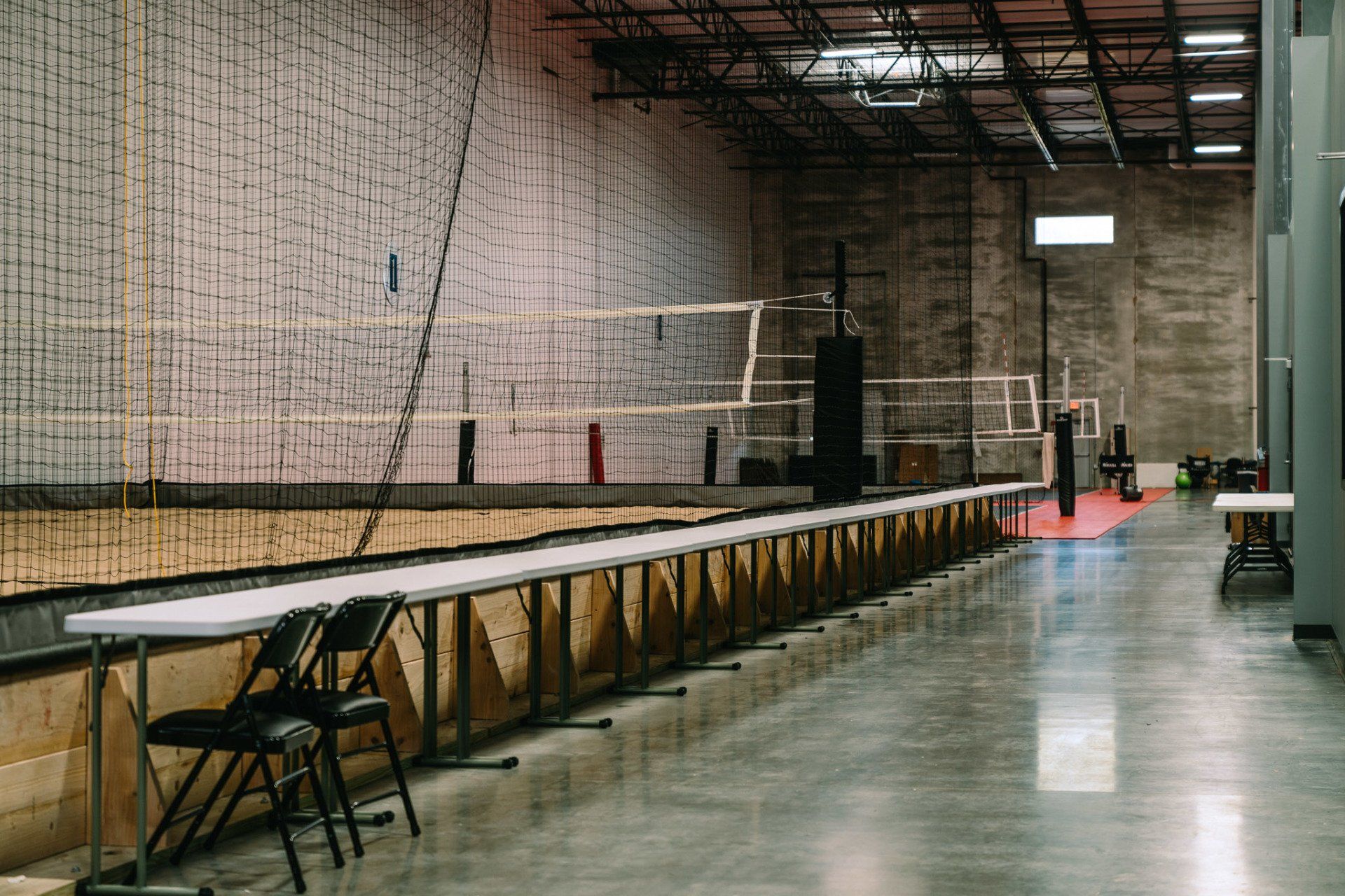 A volleyball court with tables and chairs in a warehouse.