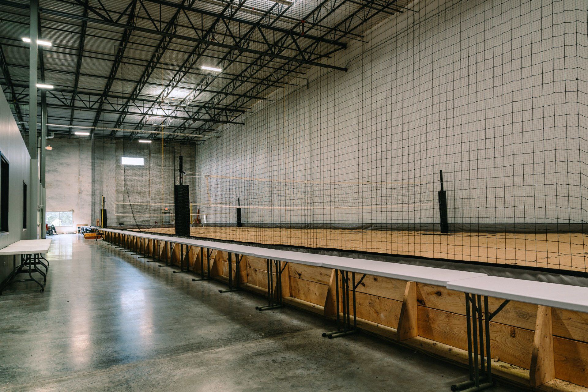 A large empty warehouse with tables and a volleyball net.