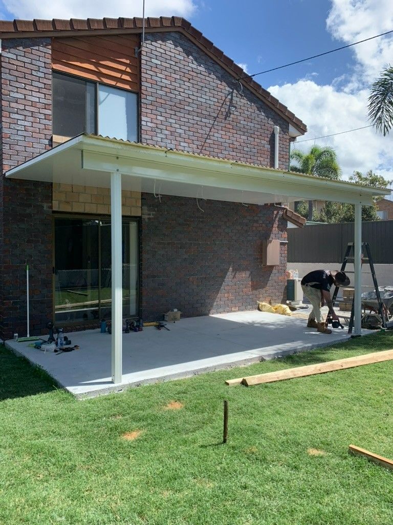 A Man is Working on a Patio in Front of a Brick House — JPR Concepts in Burleigh Heads, QLD