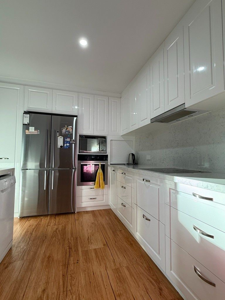 A Kitchen With White Cabinets , Stainless Steel Appliances , and Hardwood Floors — JPR Concepts in Burleigh Heads, QLD
