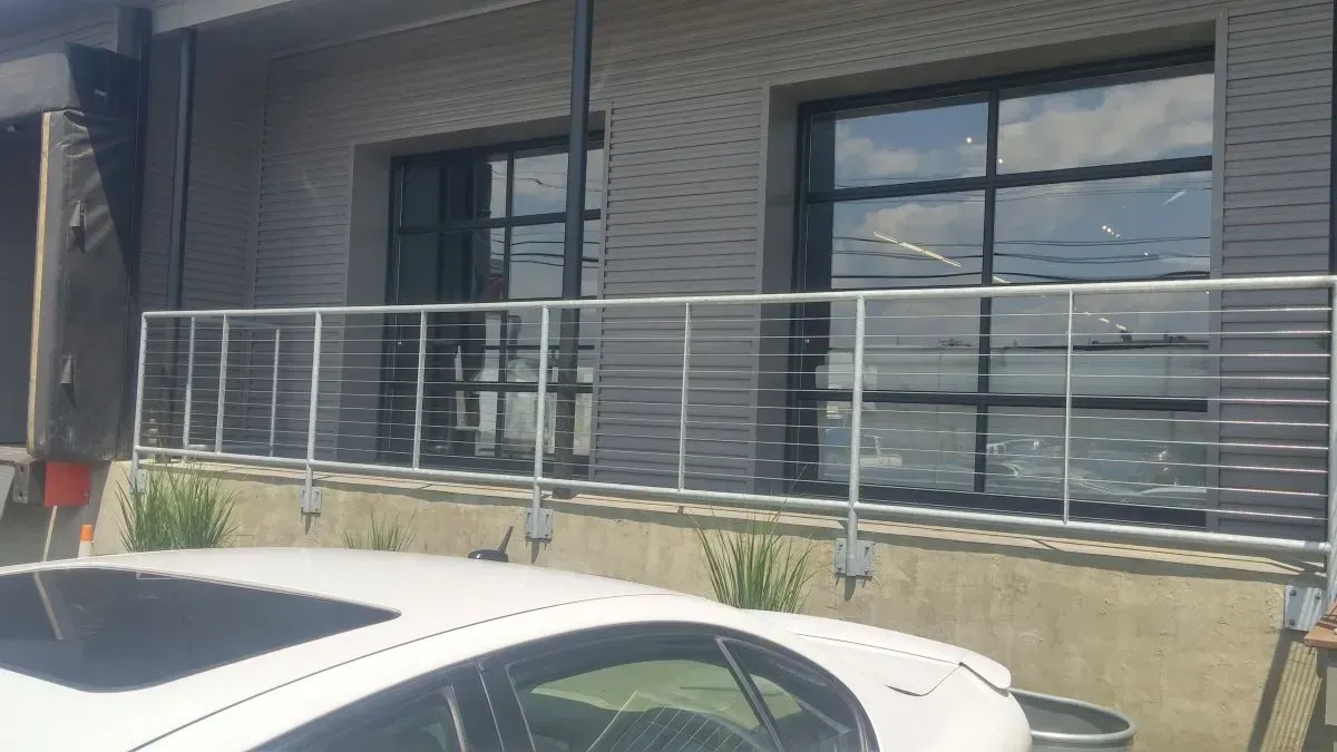 A white car is parked in front of a building with a balcony.