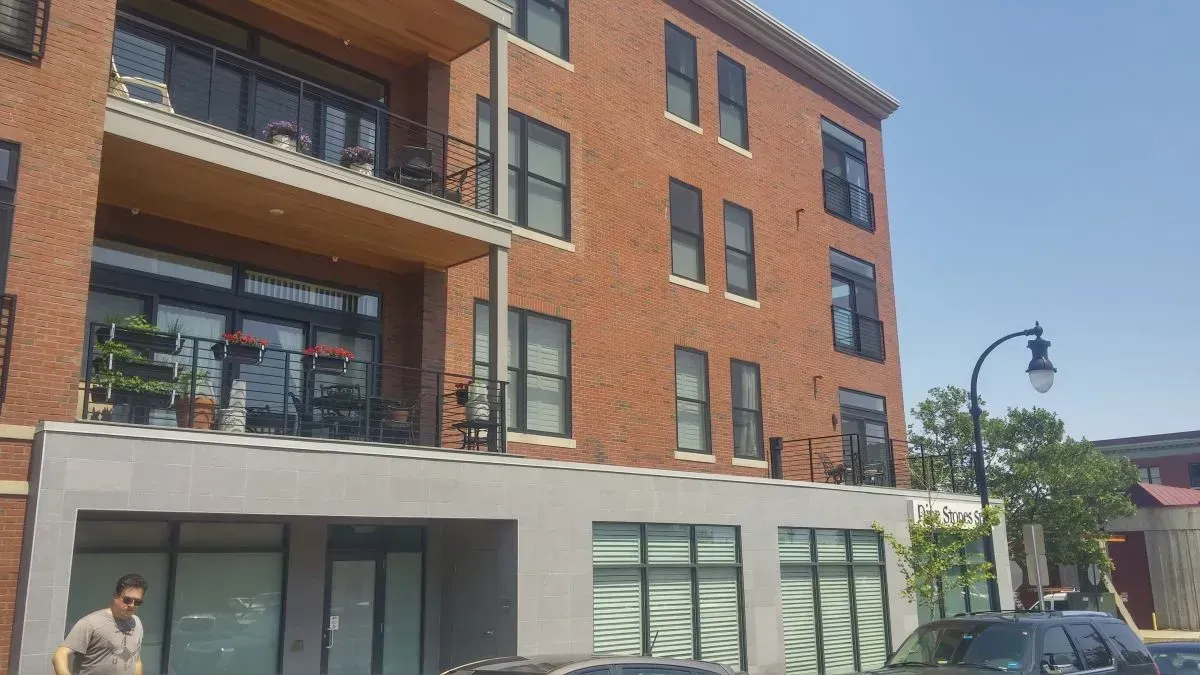 A man is standing in front of a large brick building.