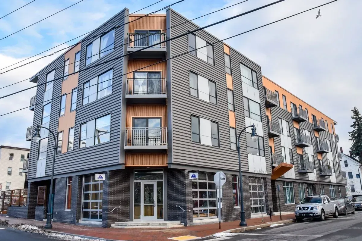 A large building with a lot of windows is on the corner of a street.