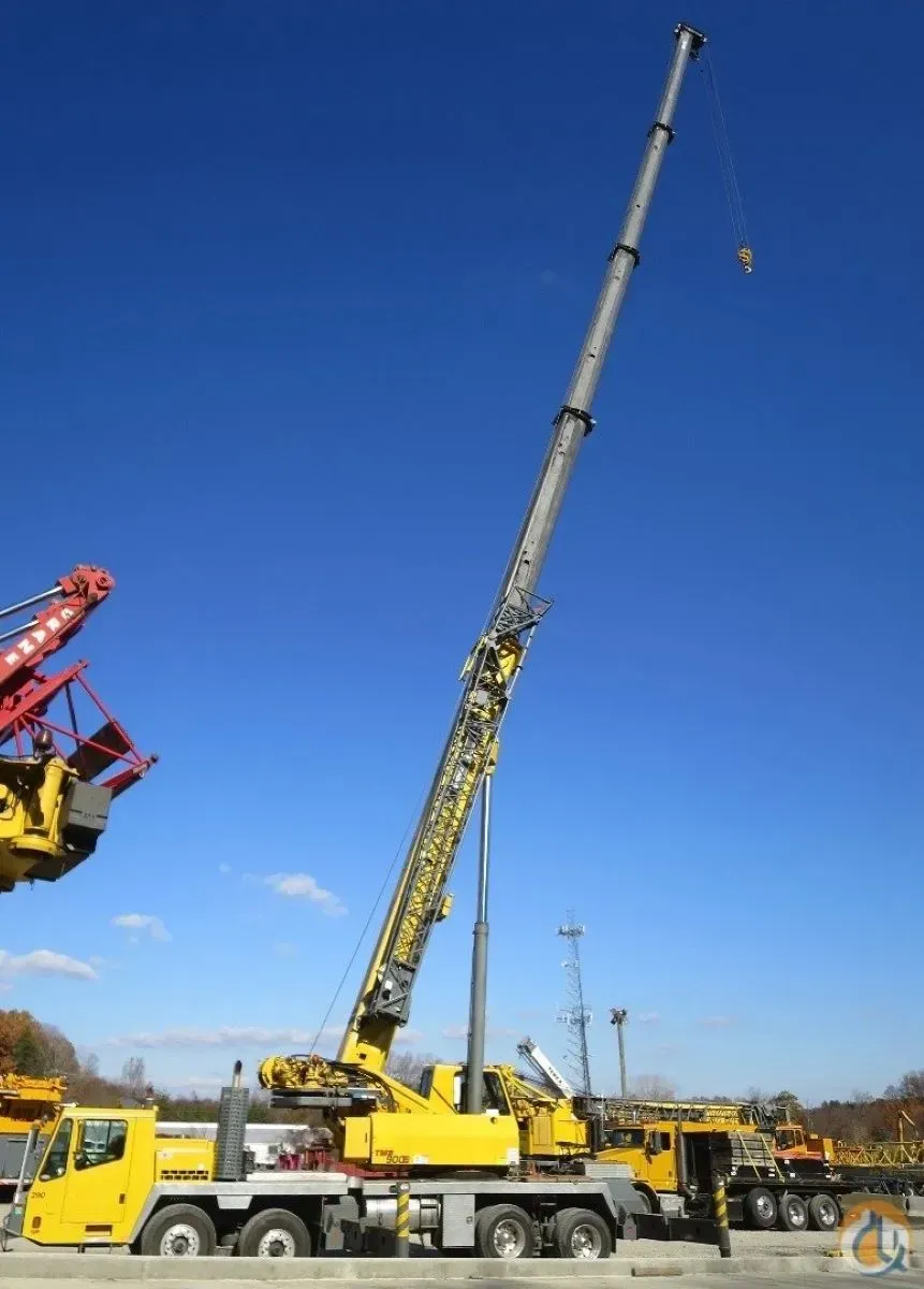 A large yellow crane is sitting on top of a yellow truck.