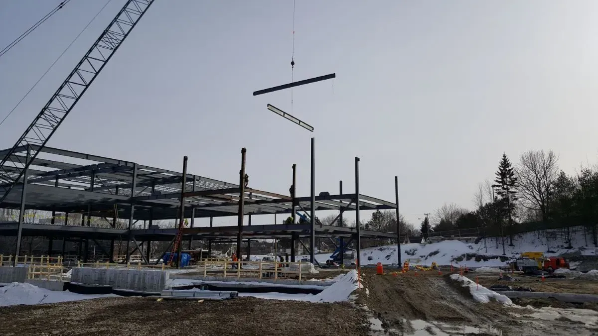 A construction site with a crane lifting a metal structure.