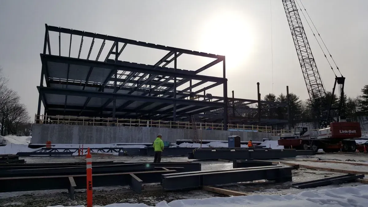 A large building under construction in the snow with a crane in the background.
