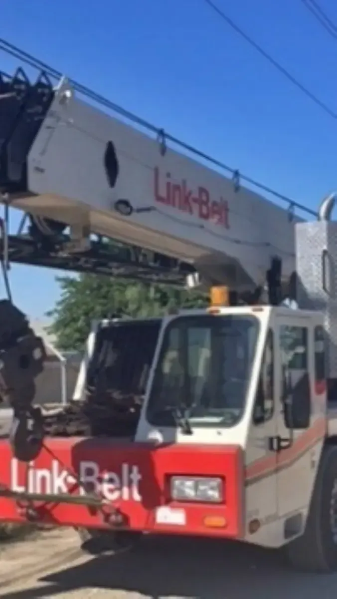 A red and white link belt truck is parked on the side of the road