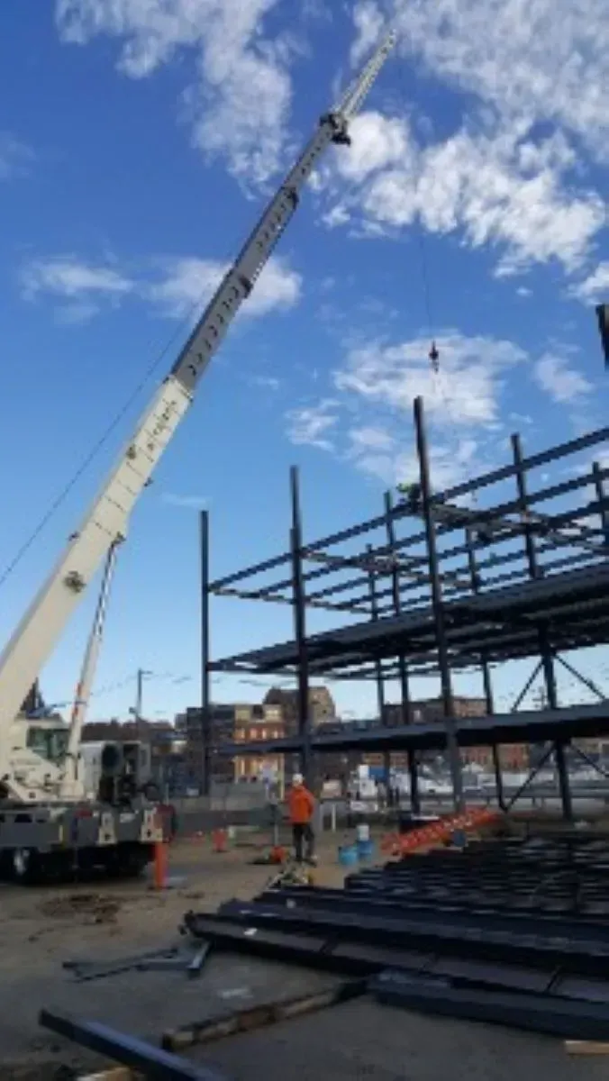 A large crane is lifting a metal structure at a construction site