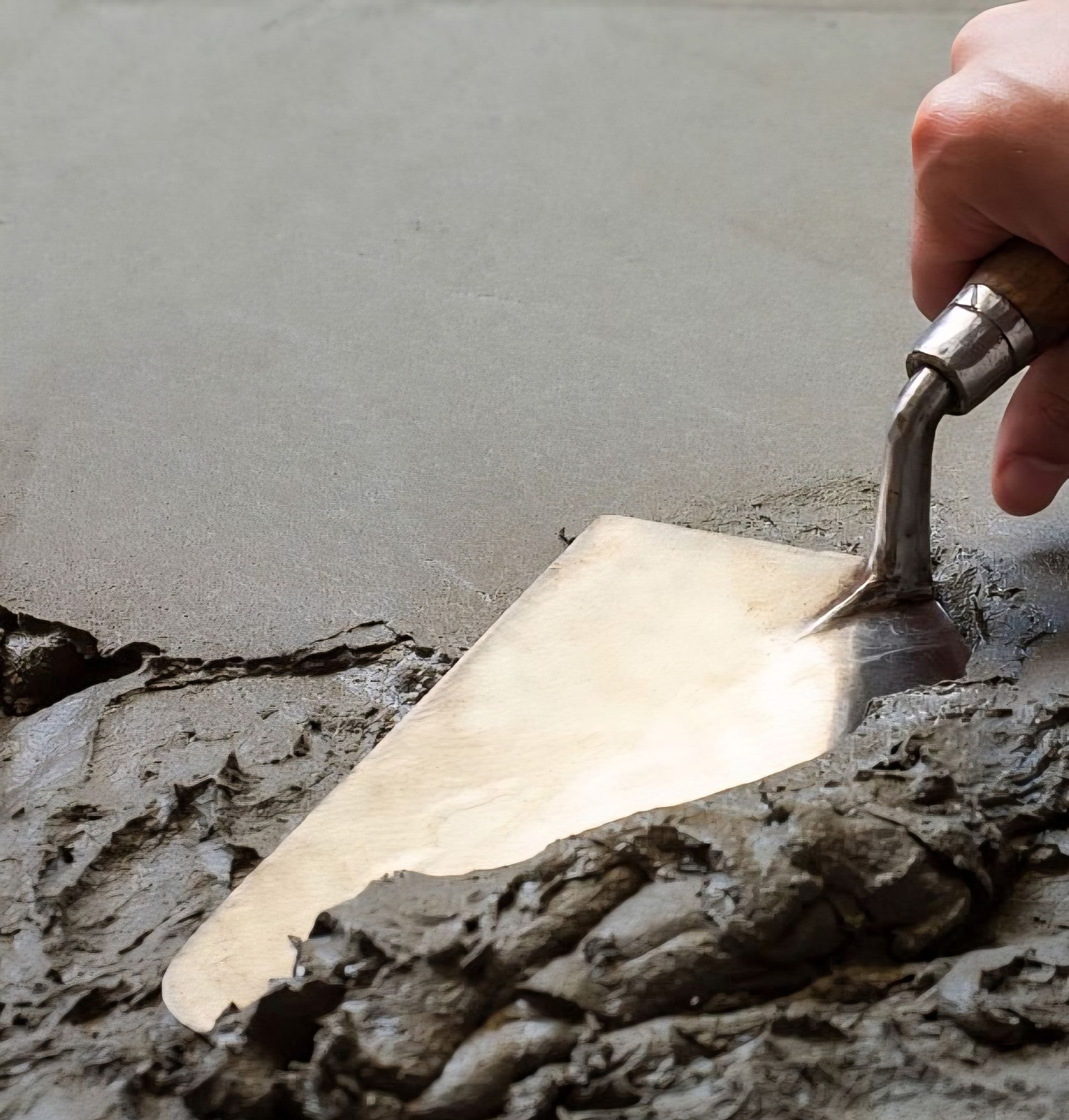 Person using a laser level and trowel to install flooring in a room.