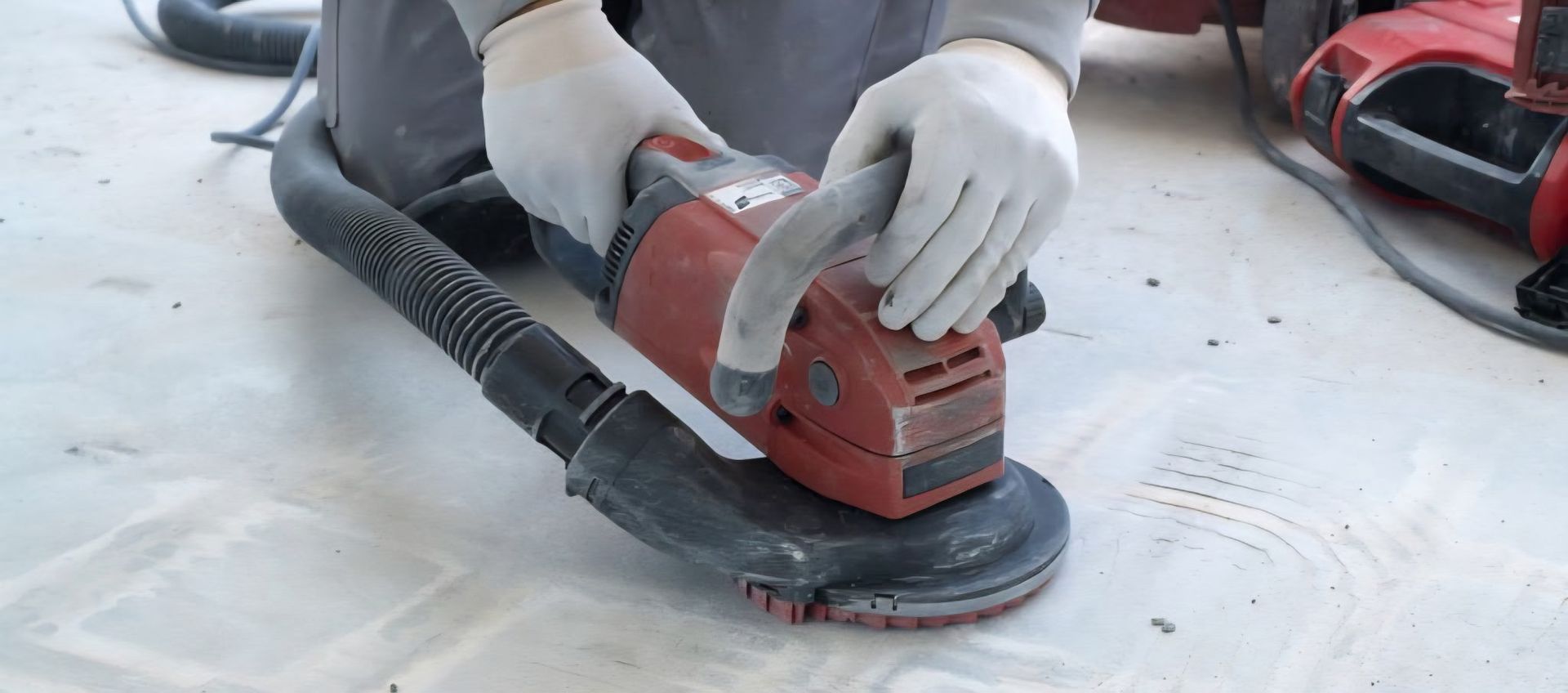 Hand with trowel spreading gray cement on a surface.