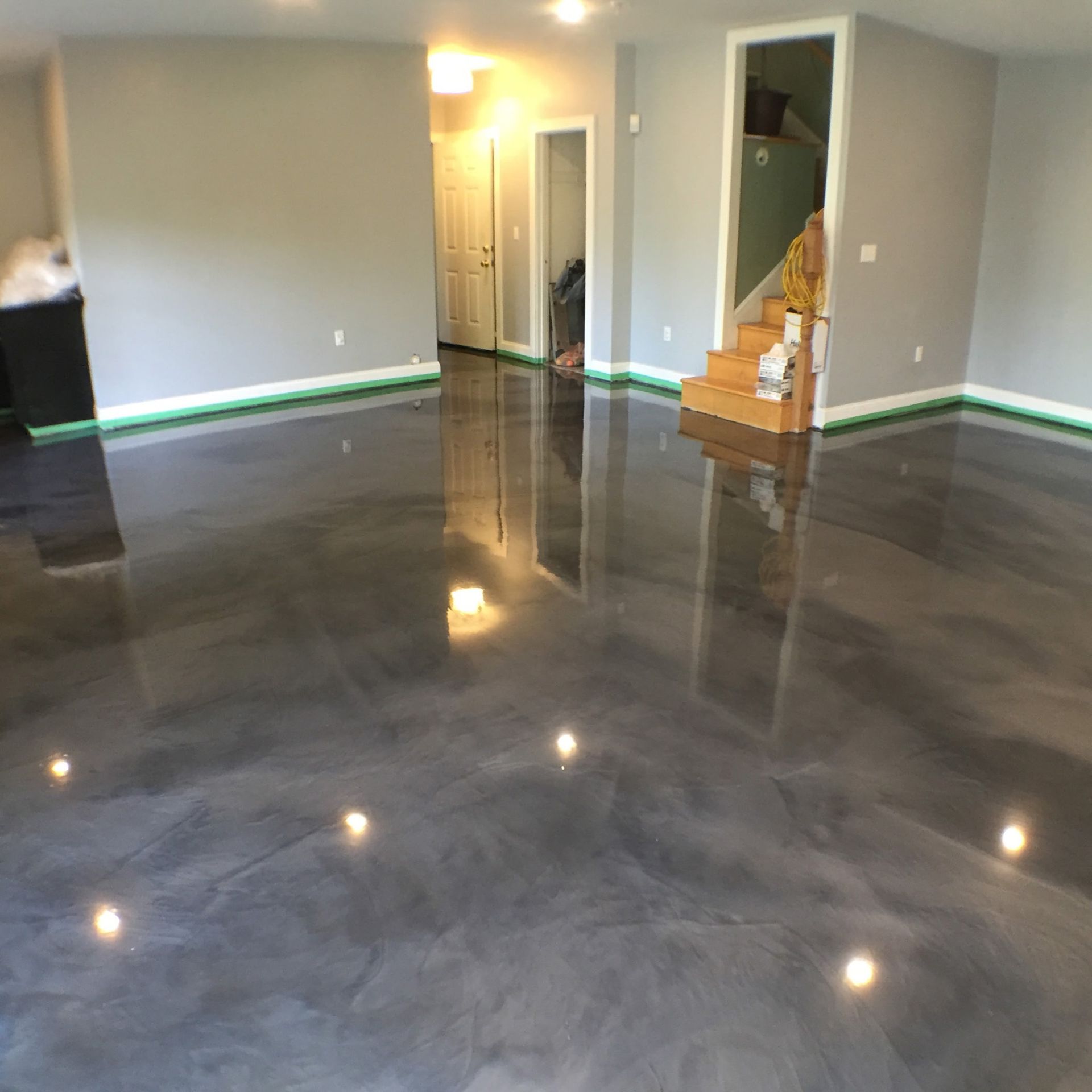 Empty, light-filled industrial space with a shiny, gray epoxy floor and windows along one wall.