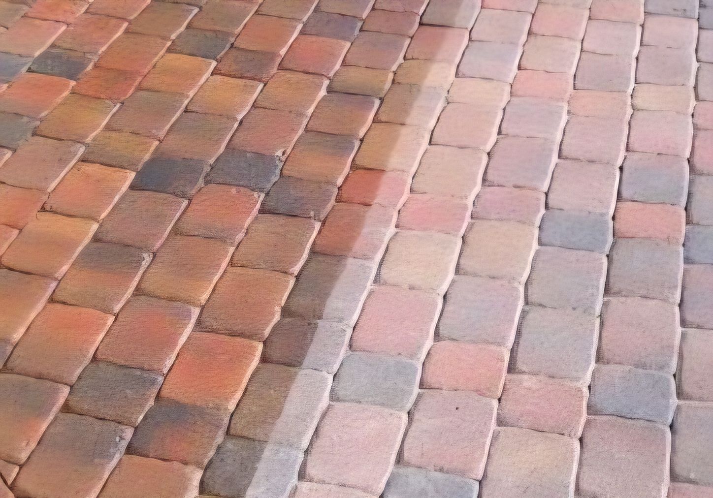 Pavers, partially cleaned by pressure washing, show the color contrast.