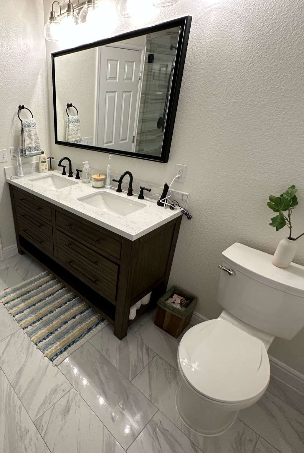 Bathroom with a wooden vanity, white countertop, large mirror, and a white toilet.