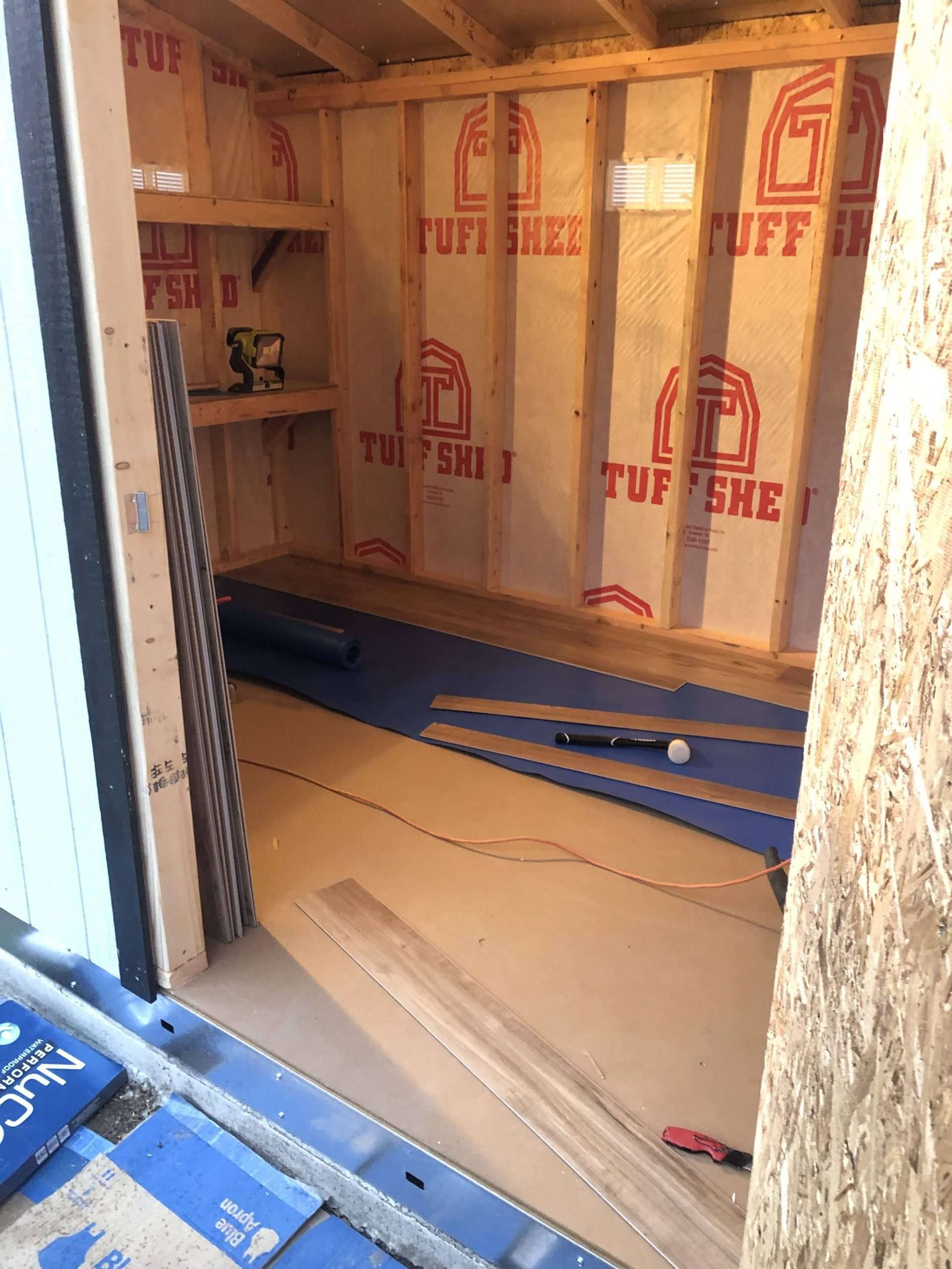 Inside view of shed with wooden frame, insulation, and construction materials.