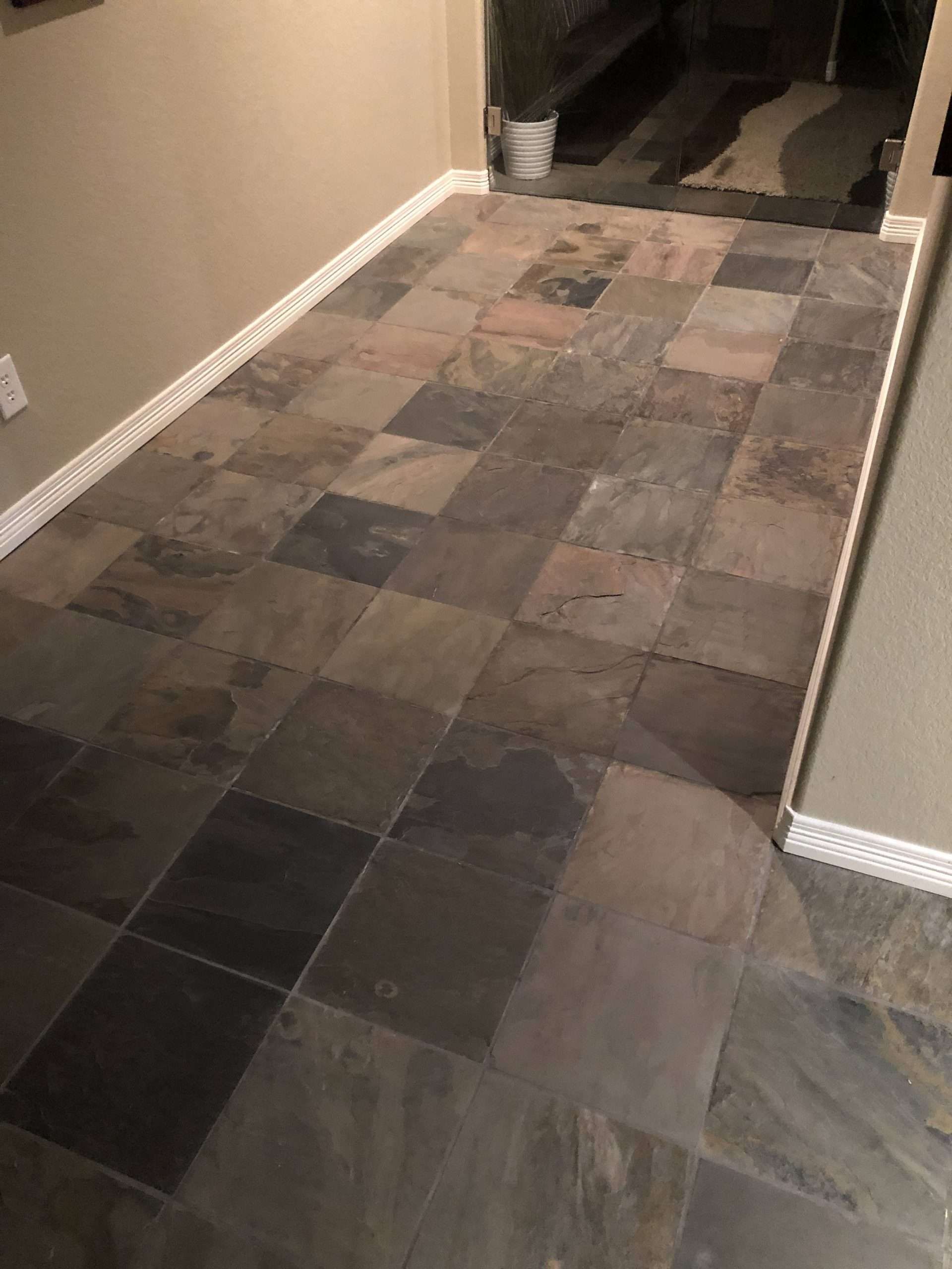 Slate tile floor in a hallway with beige walls and white baseboards.
