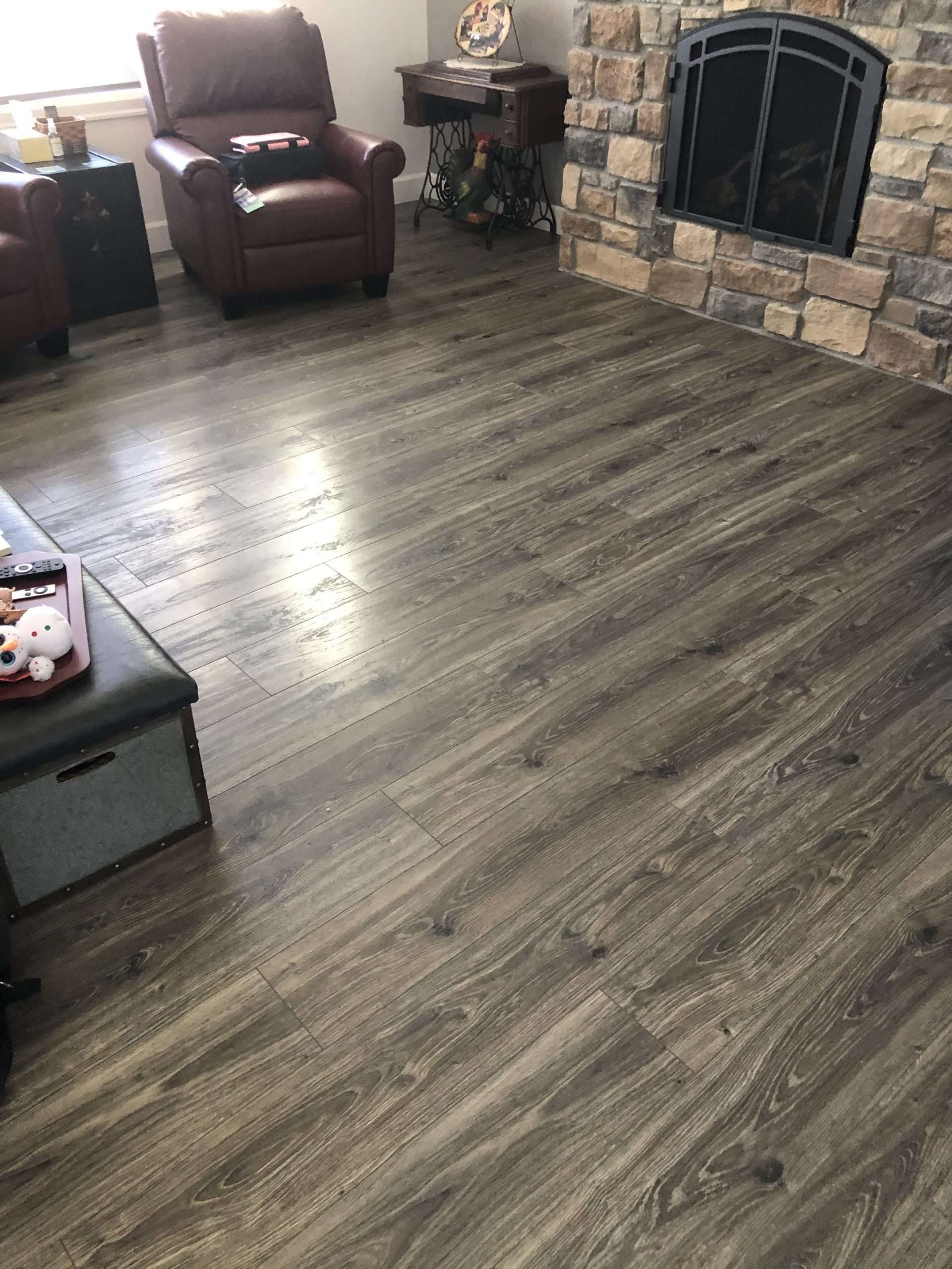Hardwood-look flooring in a living room with a fireplace and leather armchair.