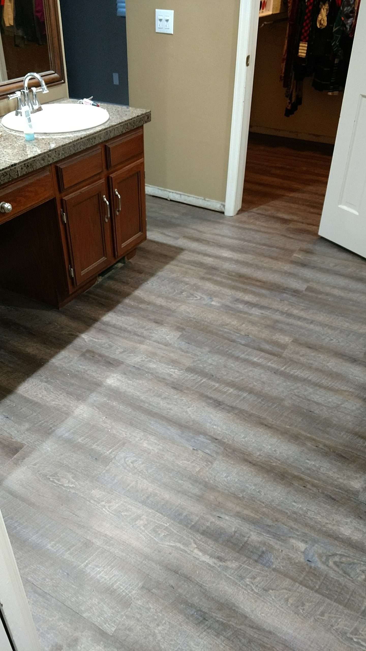 Bathroom with brown cabinets, white sink, and gray wood-look flooring.