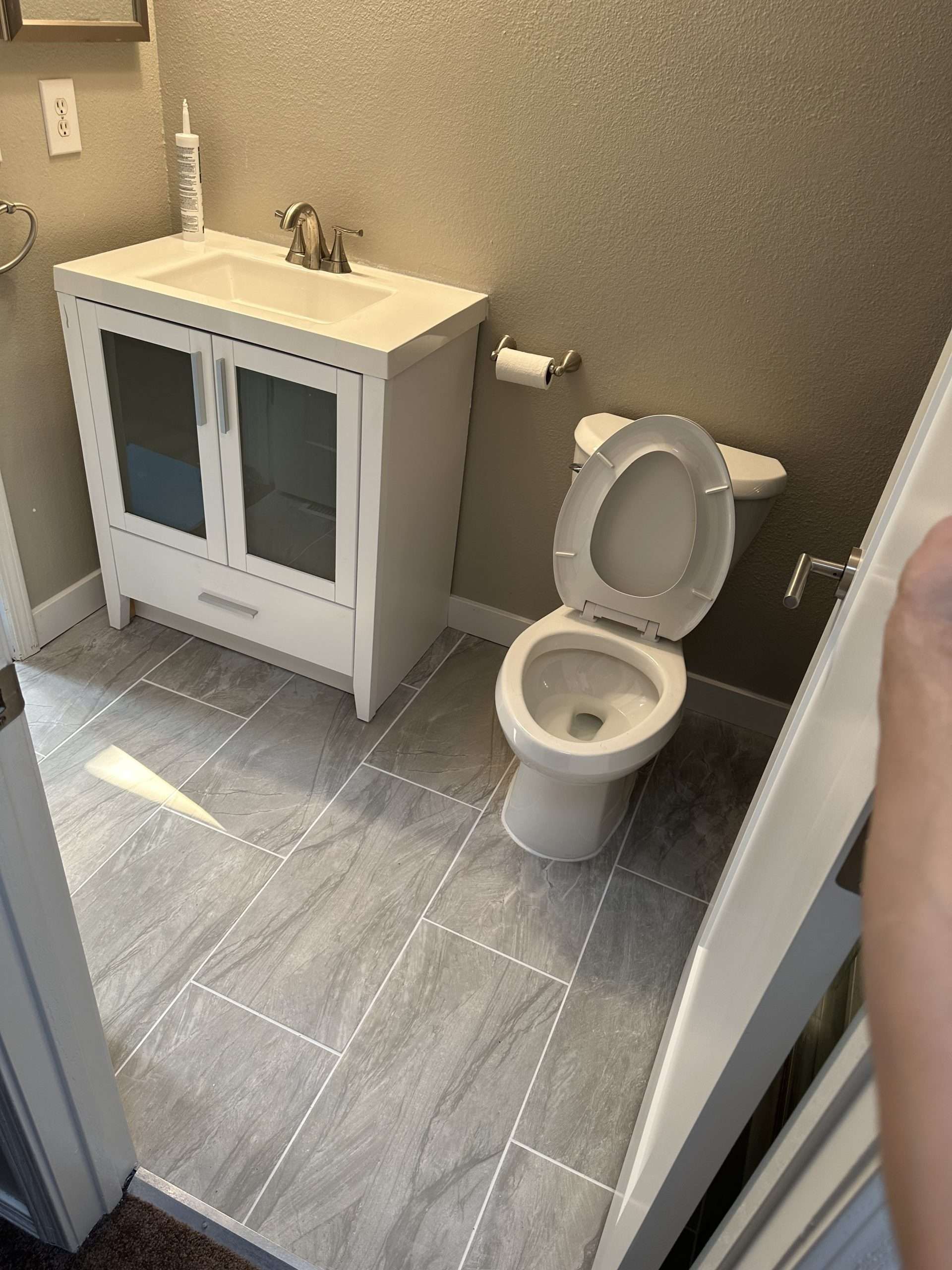 Bathroom with a white vanity, toilet, and gray tiled floor.