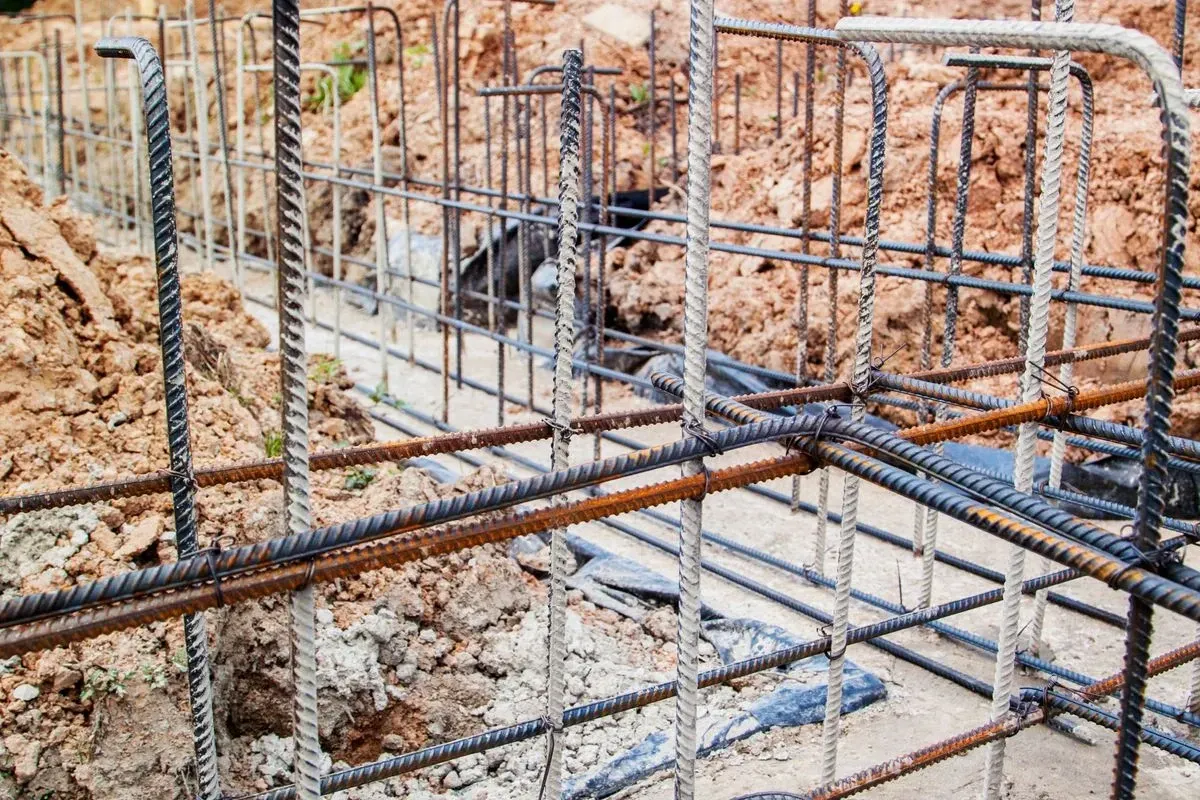 Steel rebar framework for a concrete foundation, outdoors, partially built.