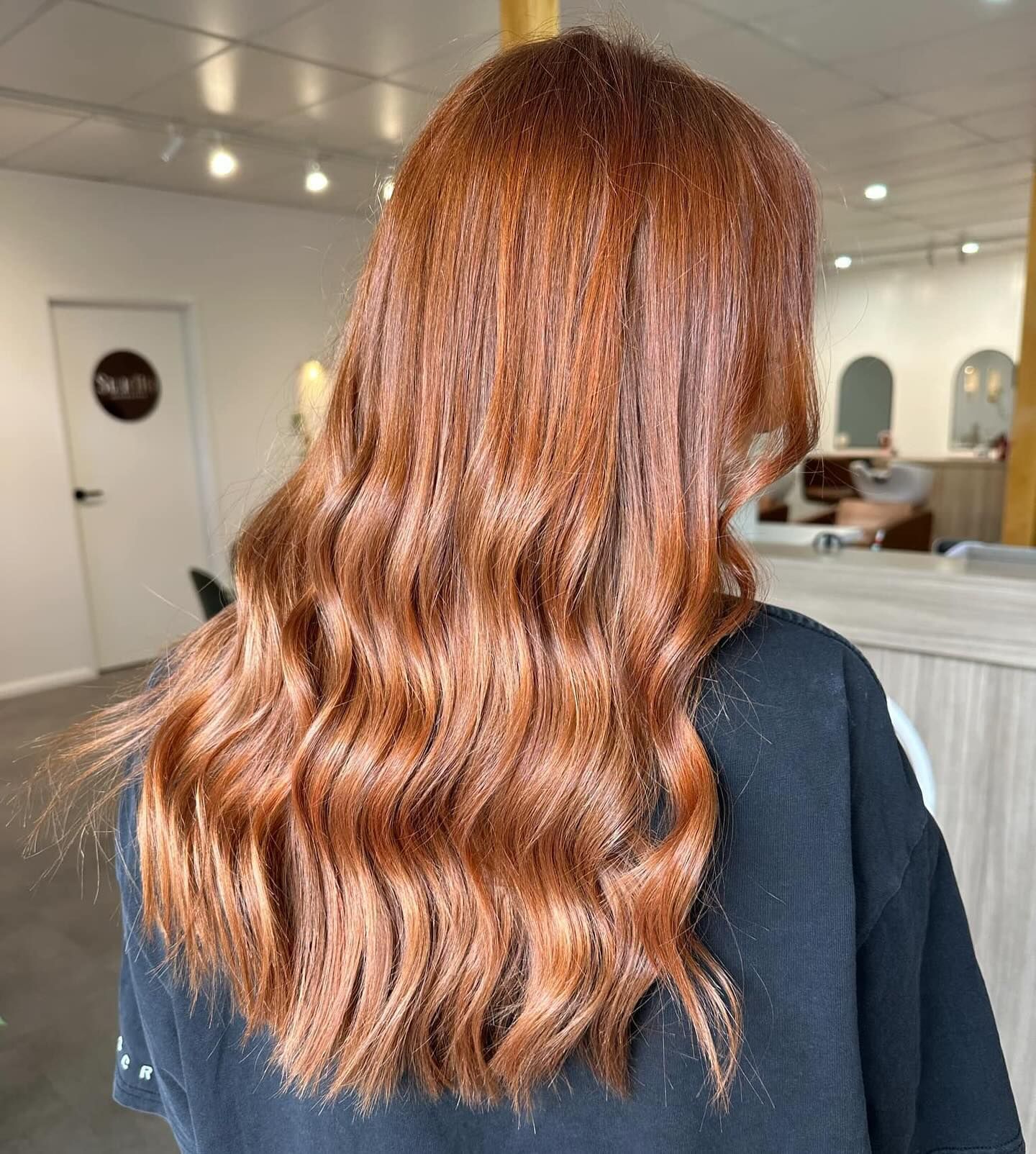 Woman's wavy, copper-colored hair in a salon. Hair is long and layered with soft waves — Salon South in Mount Sheridan, QLD