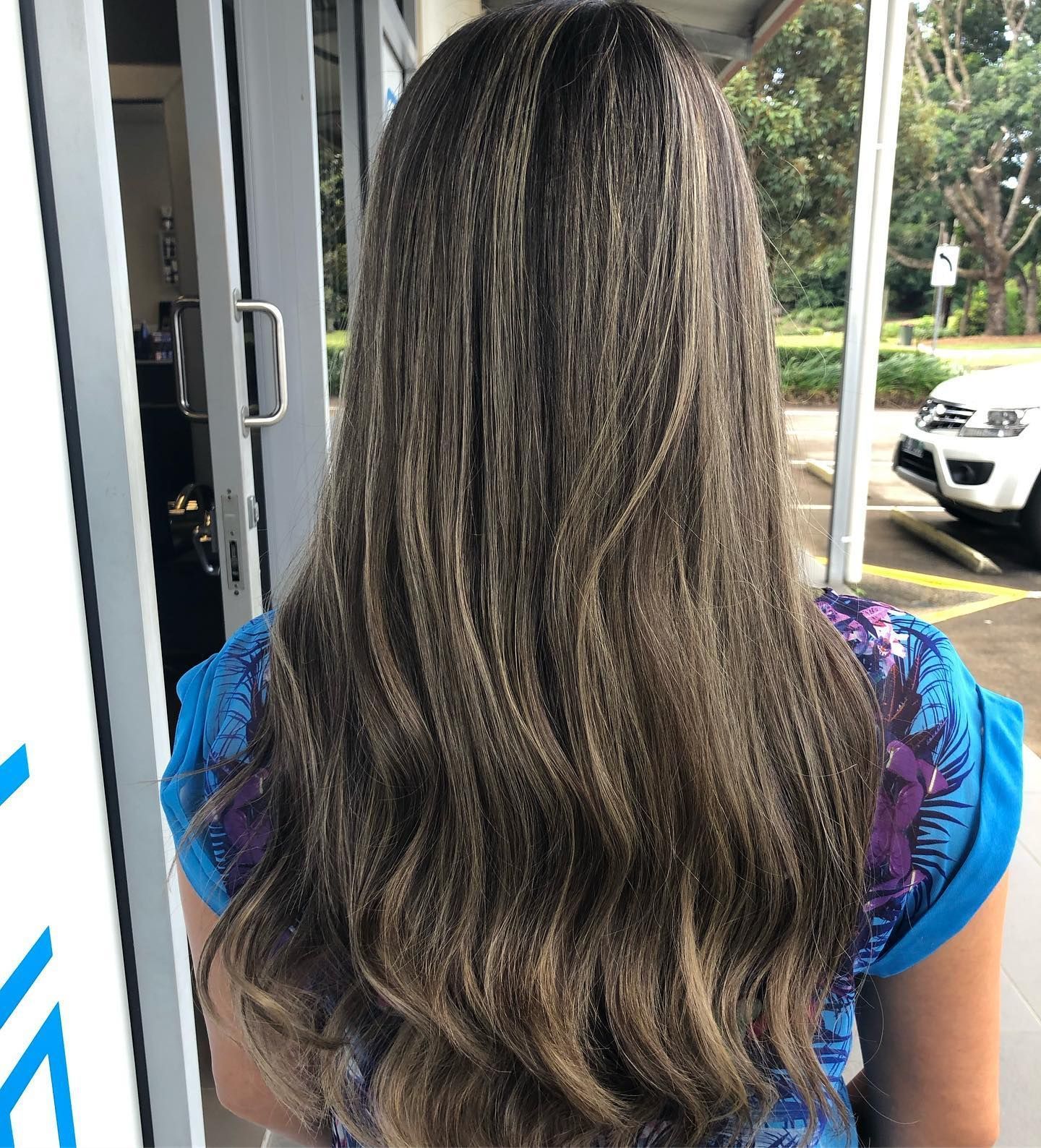 Woman With Long, Wavy Brown Hair With Blonde Highlights. Blue Patterned Shirt — Salon South in Mount Sheridan, QLD
