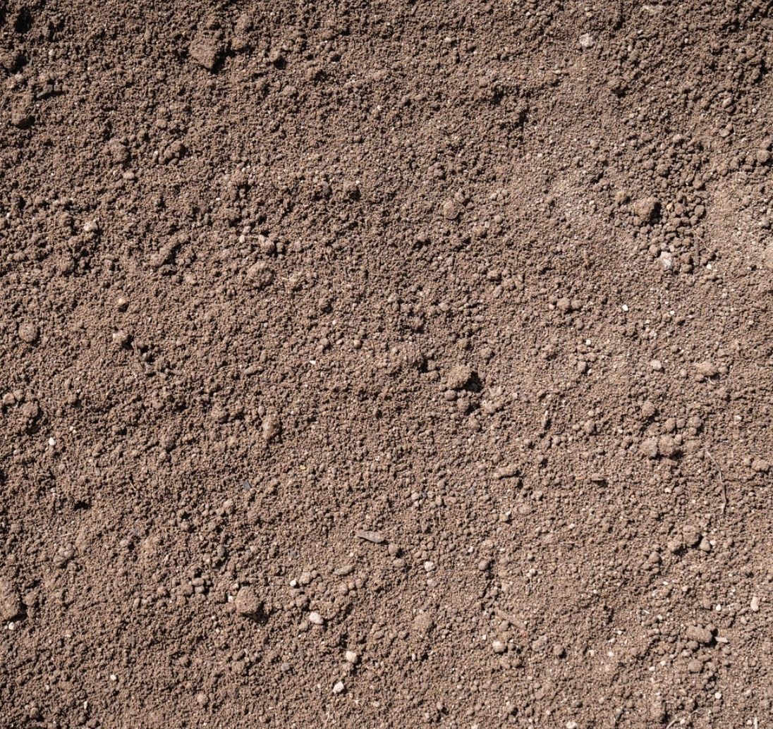 Close-up of brown soil with clumps and small sticks.