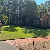 A man is using a shovel to spread gravel on a patio.