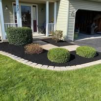 A man wearing a hat is laying bricks on a sidewalk.