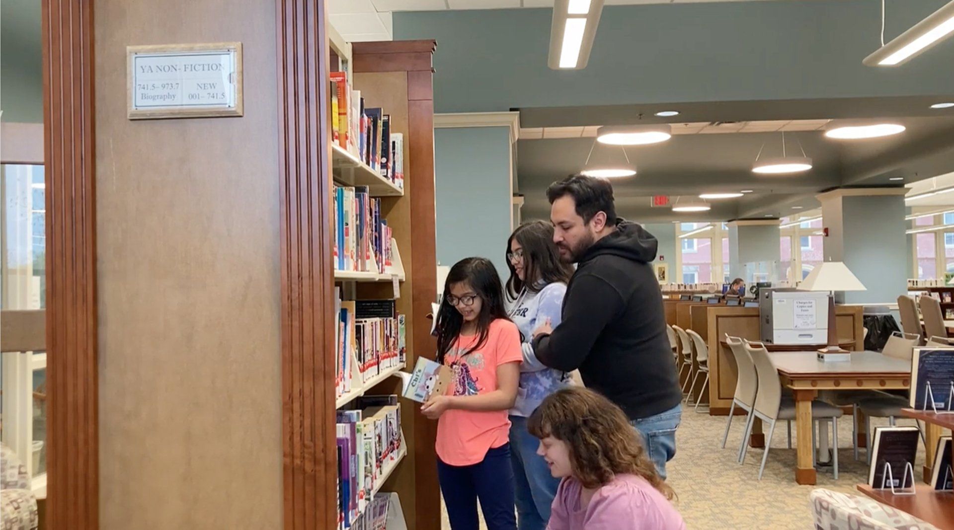 Latino family searching book shelves