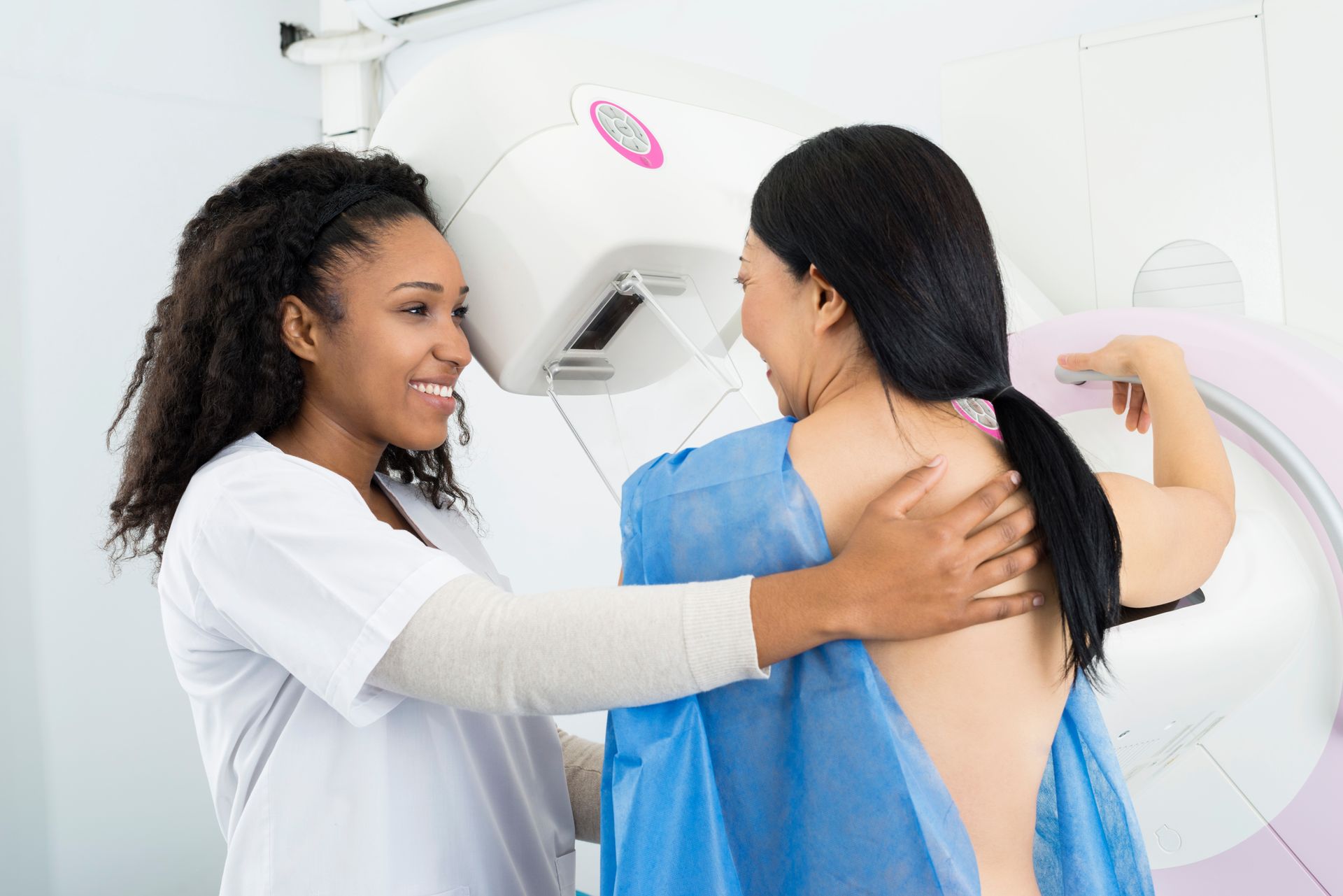 Happy doctor assisting woman undergoing mammogram x-ray test.