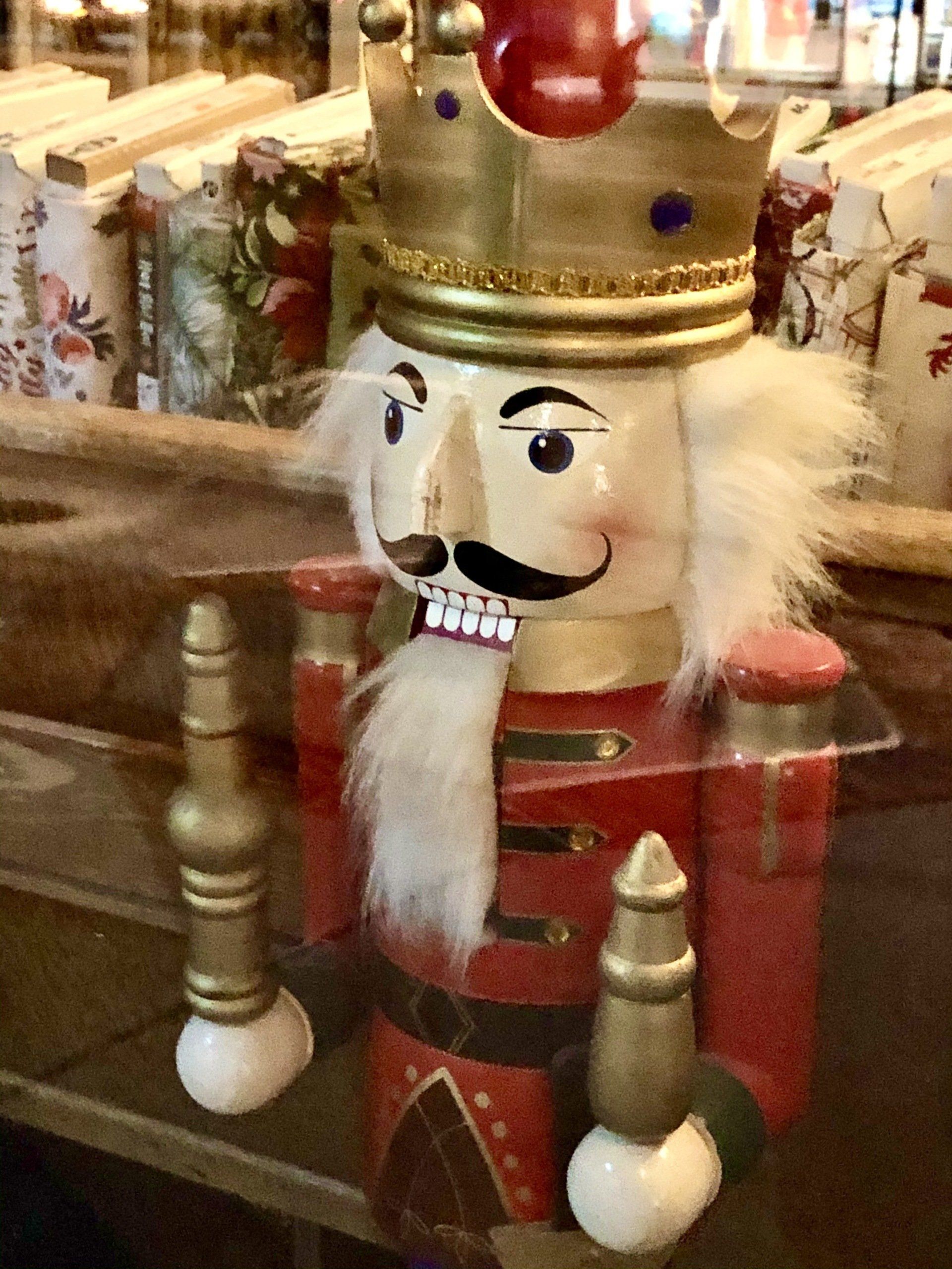 A nutcracker with a crown on his head is sitting on a table.