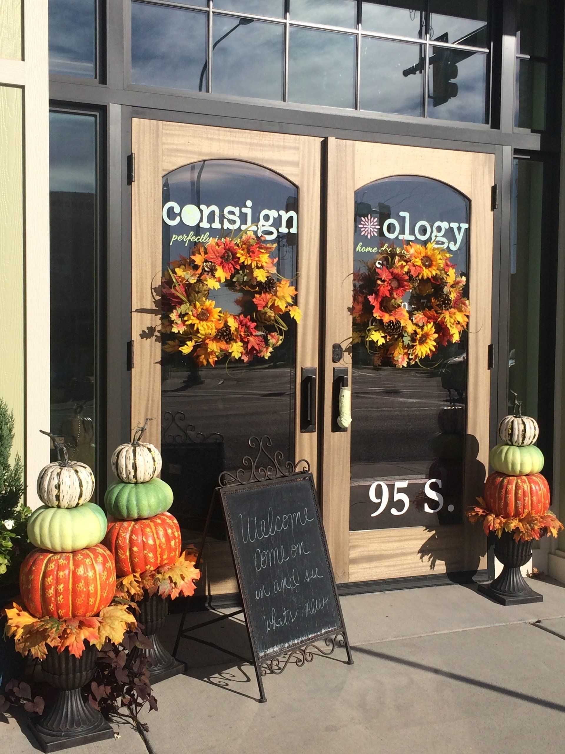 A store front with pumpkins and a sign in front of it.