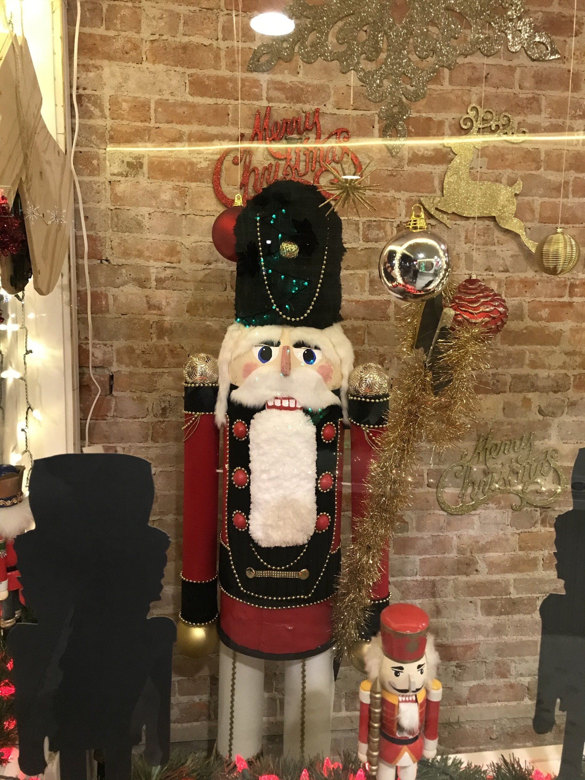 A large nutcracker is standing in front of a brick wall.