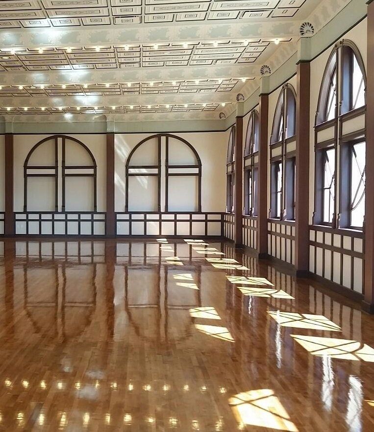 A large room with arched windows and a wooden floor