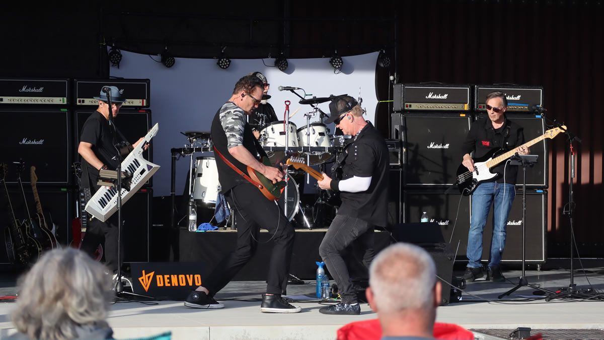 A band is playing on a stage with a banner that says Myer's Morturary