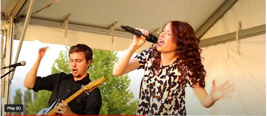 A man is playing a guitar and a woman is singing into a microphone.