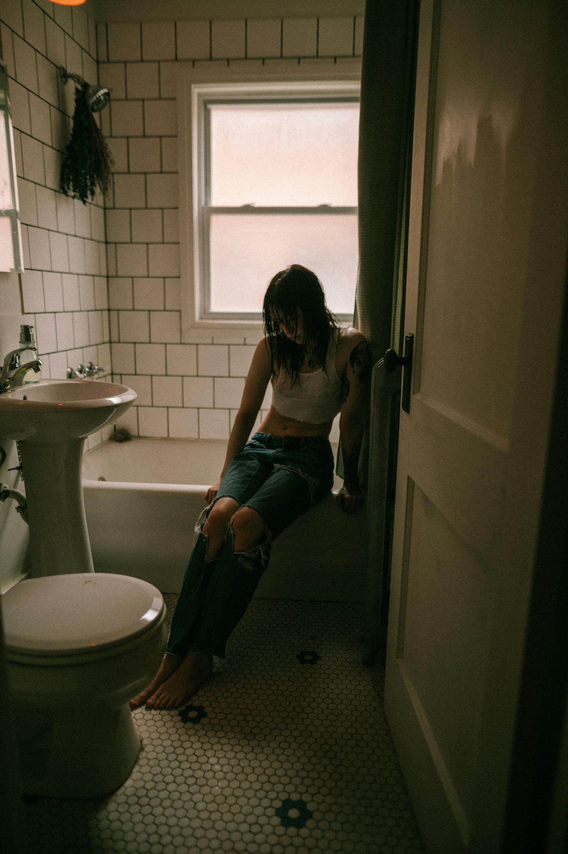A woman is sitting on a bathtub in a bathroom.