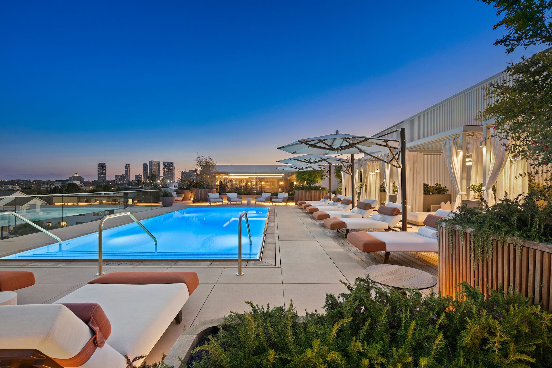 A large swimming pool is surrounded by lounge chairs and umbrellas.