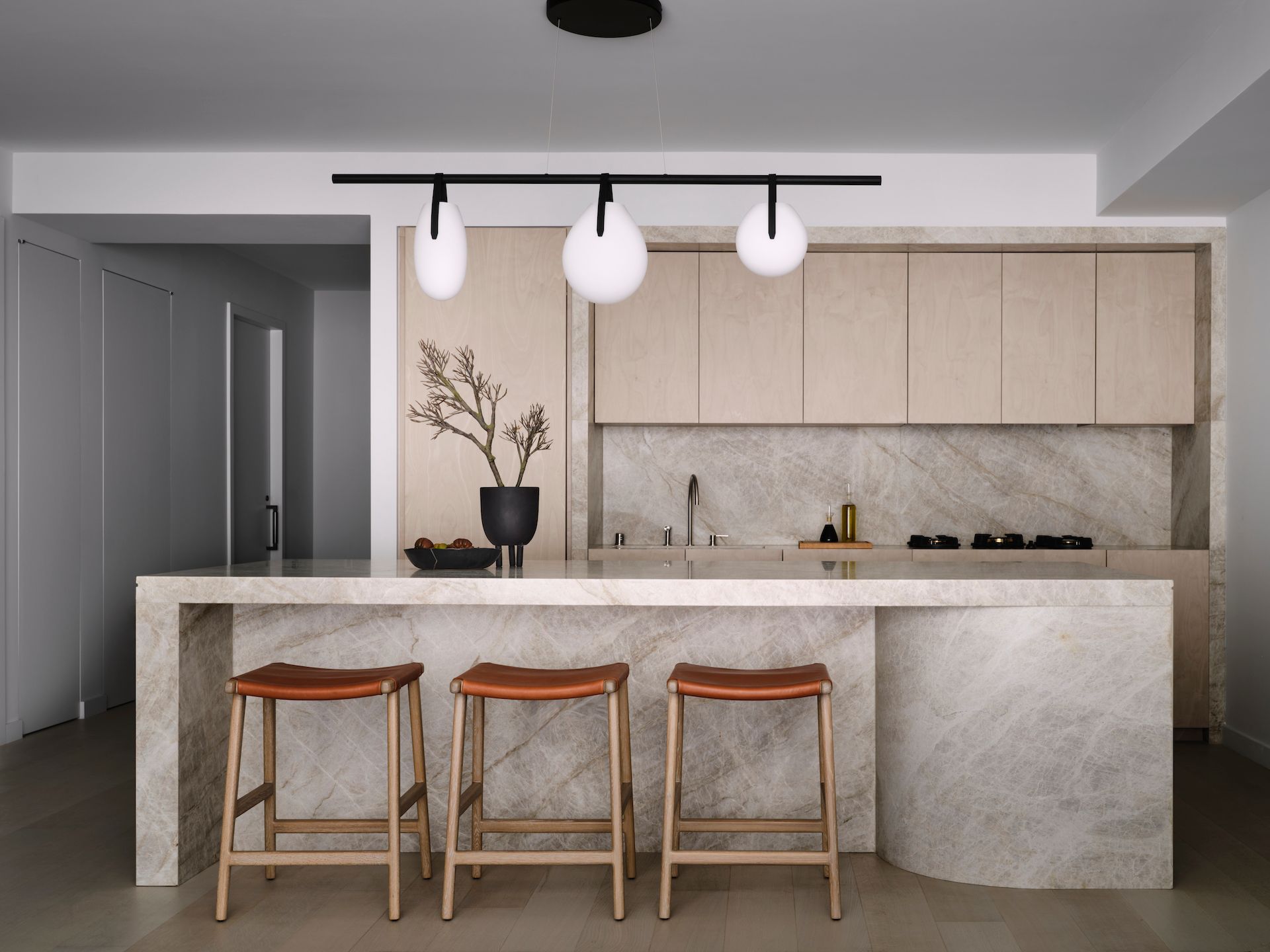 A kitchen with a large island and three stools.