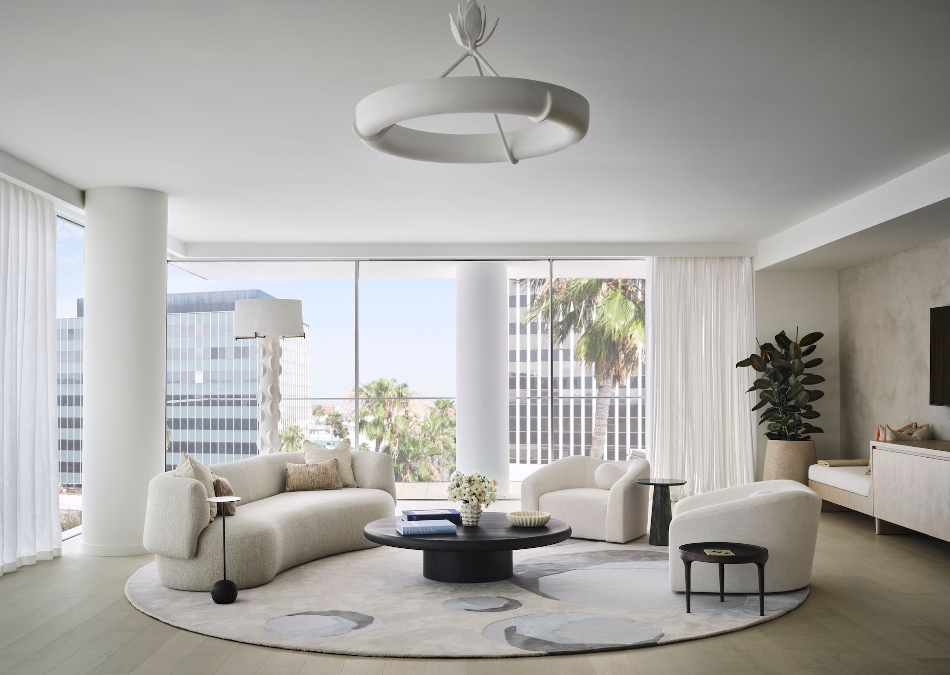 A living room with a curved couch , chairs , and a round rug.