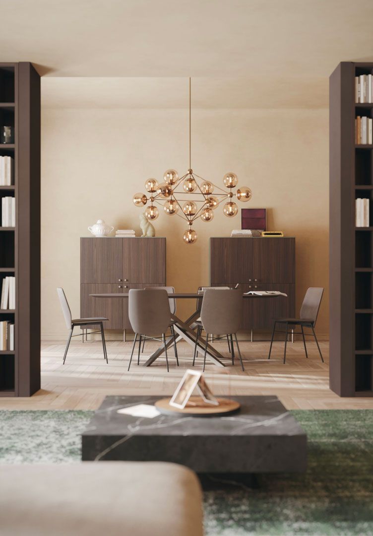 Sala da pranzo con tavolo, sedie, mobili e lampada a sospensione. Librerie fiancheggiano lo spazio.