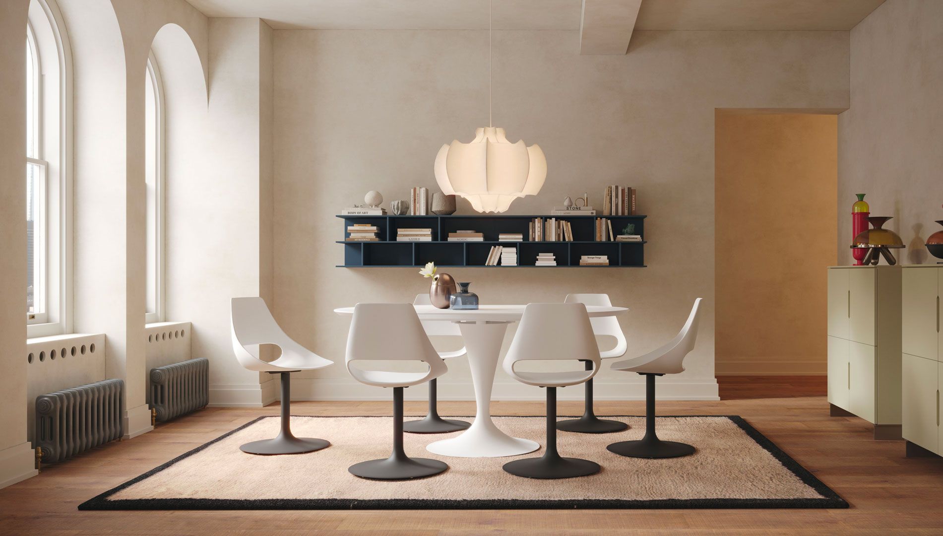 Sala da pranzo con tavolo bianco Tulip, sedie e lampada a sospensione, con tappeto, scaffali e credenza.