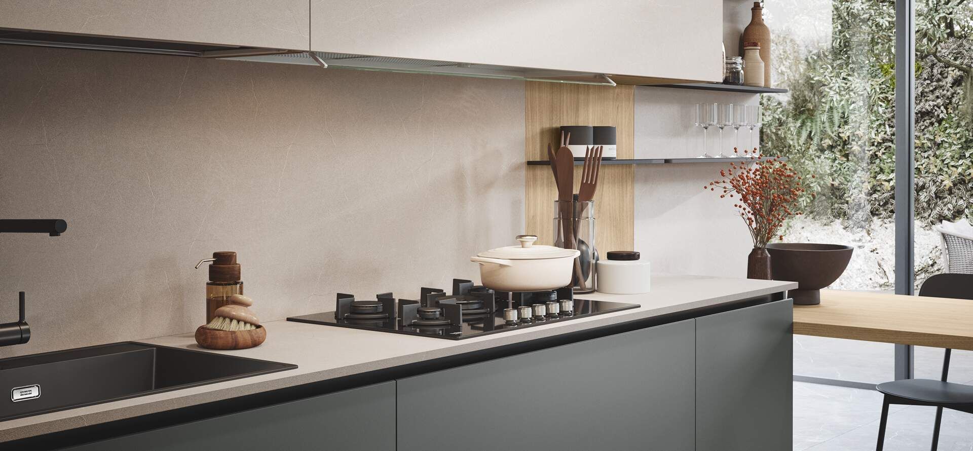 Cucina moderna con mobili grigi, piano cottura e lavello; finestra con vista sul verde.