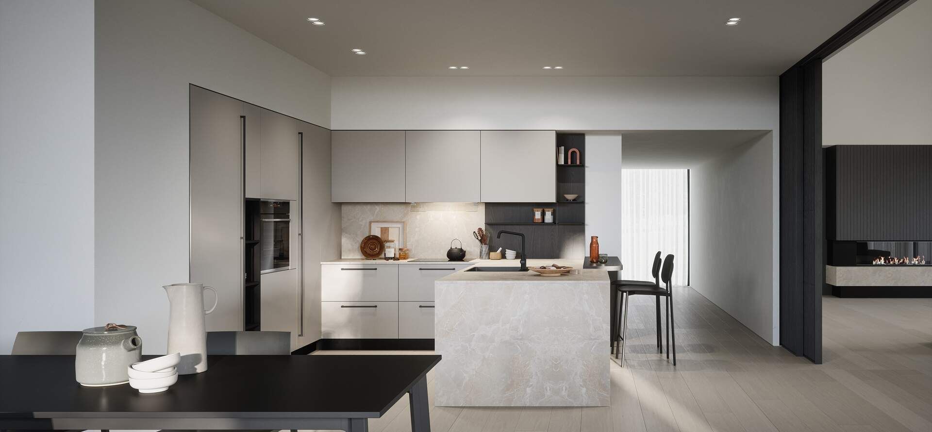 Cucina moderna con mobili grigio chiaro, isola e tavolo da pranzo. Una porta si apre su un soggiorno con camino.