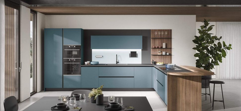 Cucina moderna con mobili color verde acqua, isola in legno e tavolo da pranzo.