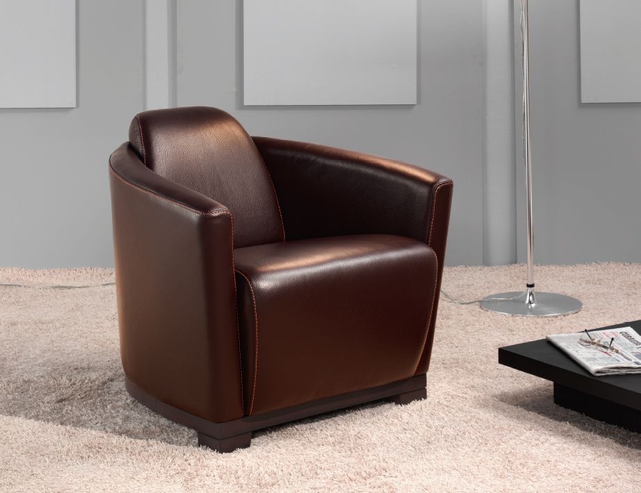 Poltrona in pelle marrone in un soggiorno moderno con tappeto e tavolino.