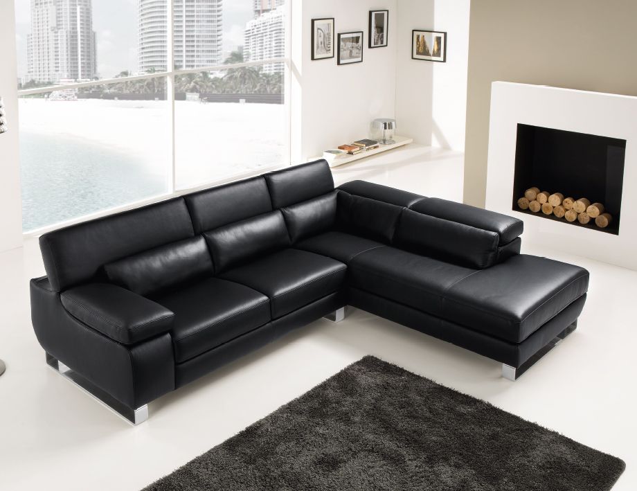 Divano componibile in pelle nera in un soggiorno moderno con camino.