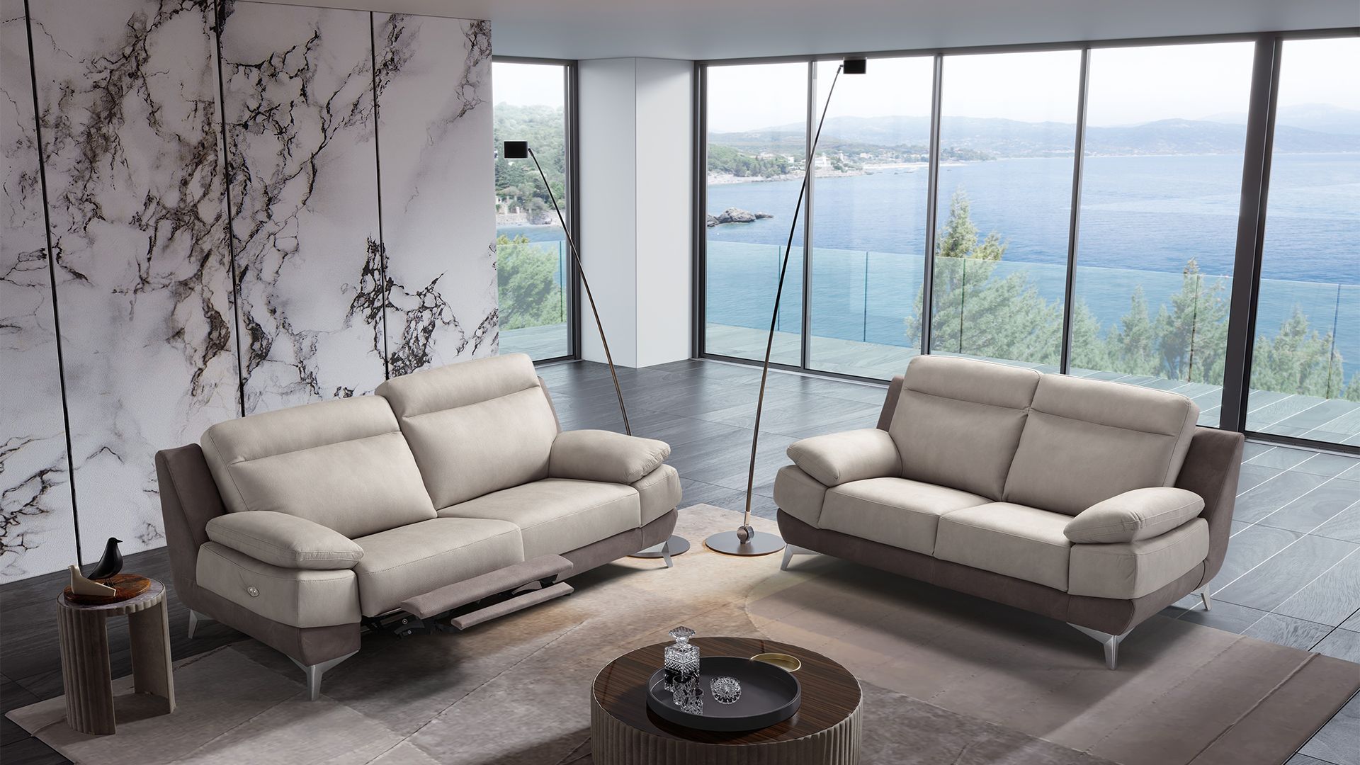 Soggiorno moderno con divani in pelle beige, parete in marmo e vista panoramica sul lago.