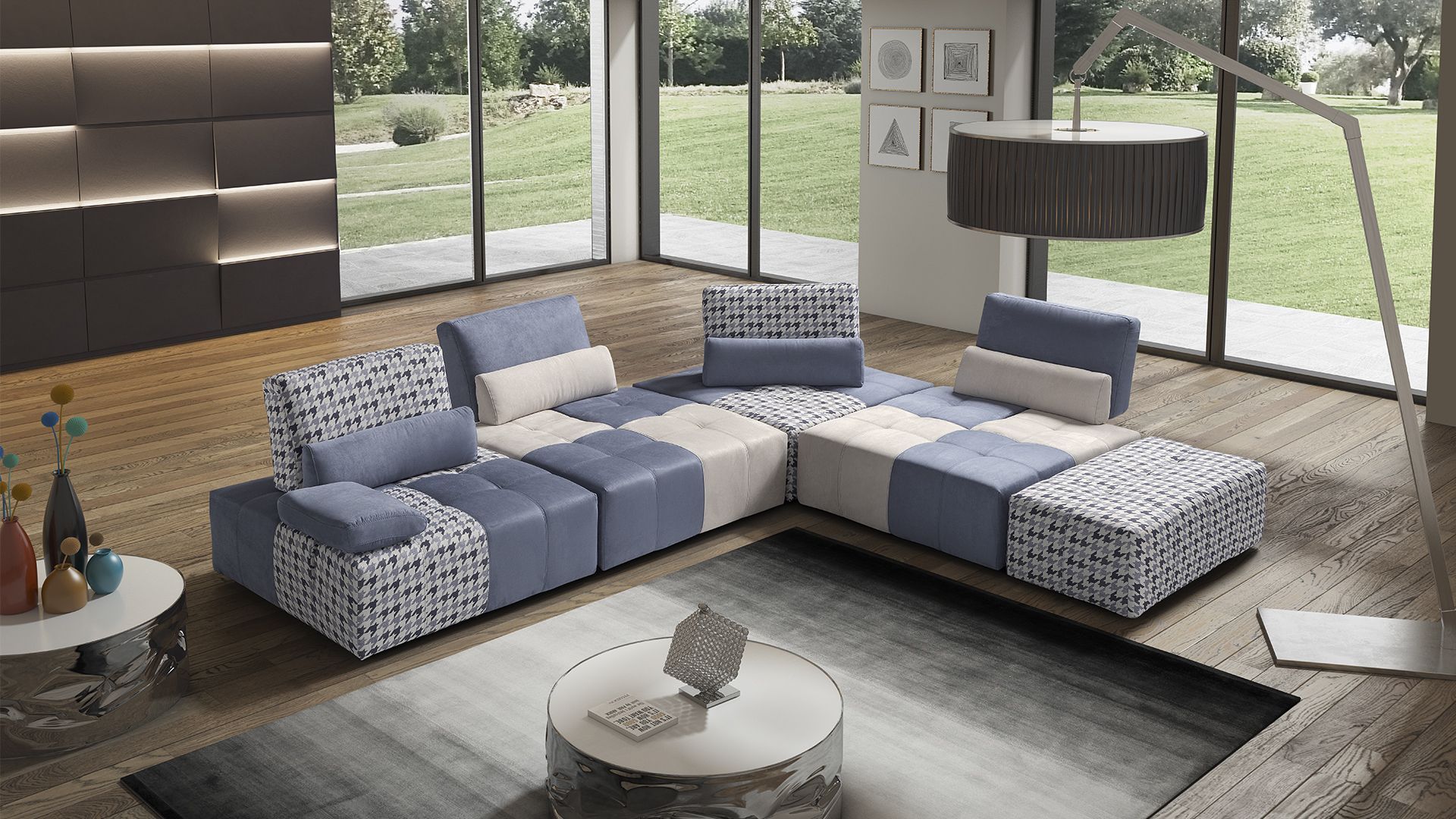 Soggiorno moderno con divano componibile blu e bianco, tappeto e una grande finestra che si affaccia sul cortile.